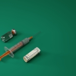 A syringe, a COVID vaccine and a rolled up banknote. Health and