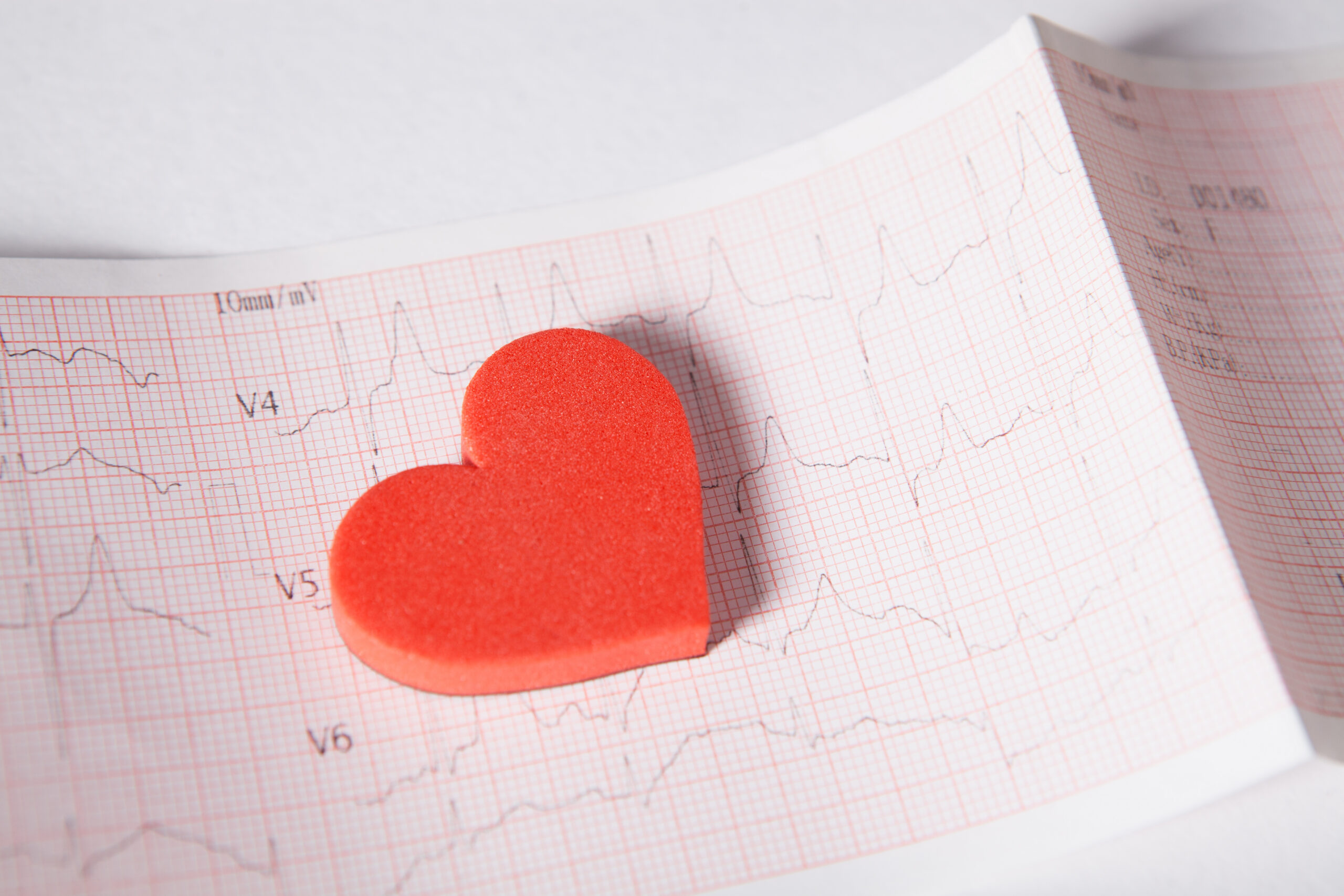 Red foam heart resting on an electrocardiogram tracing, suggesting heart health or Valentine's theme.