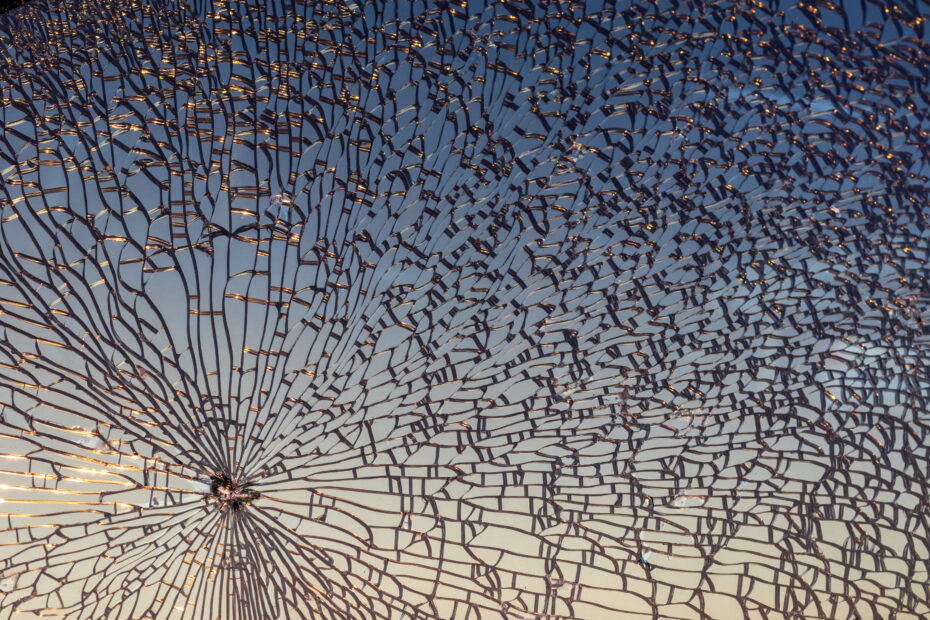 Dandelion-inspired metal sculpture with radiating spokes silhouetted against a sunset sky at dusk, an outdoor art installation.