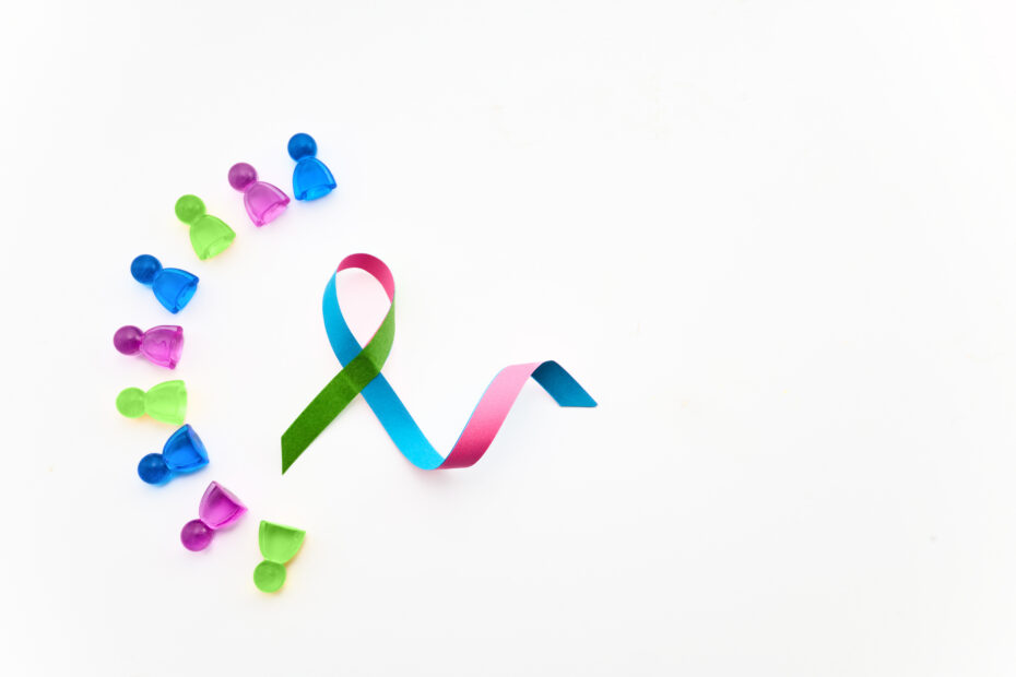 Assorted neon push pins laid out in a curved line with rainbow curling ribbons on a white background.