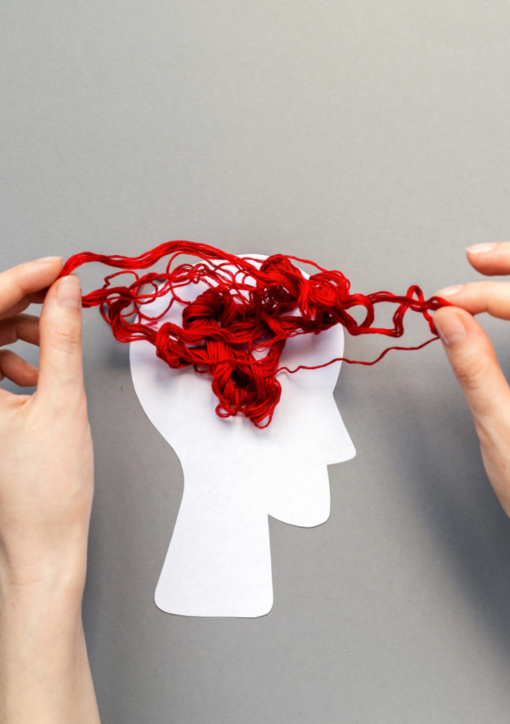 A human head paper cut out with tangled red yarn above symbolising the brain