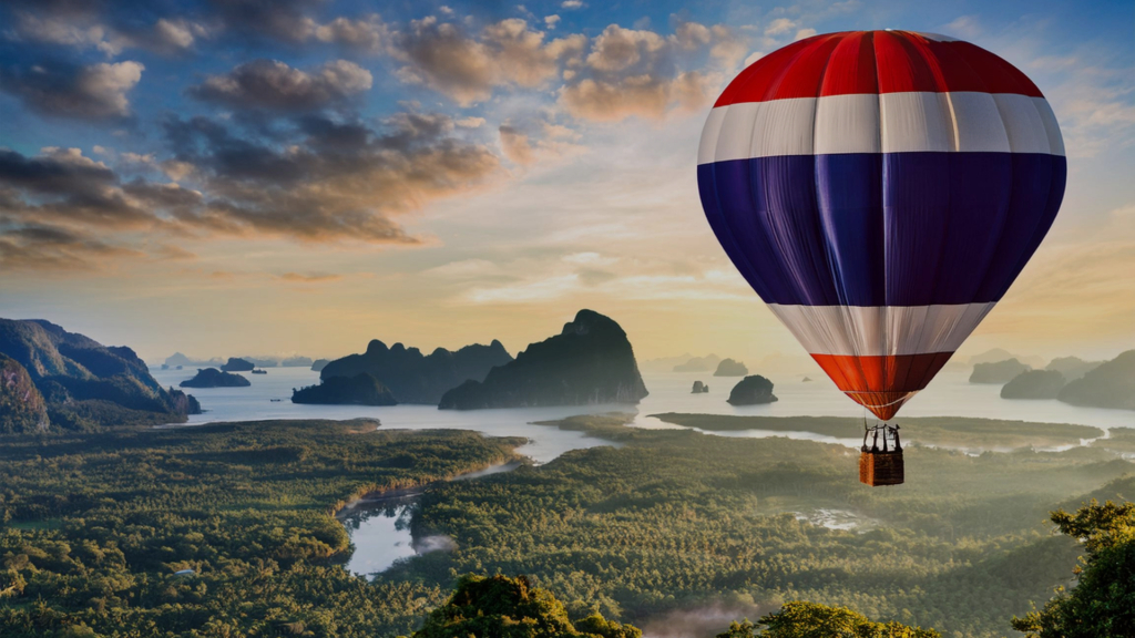 A hot air balloon flying in the colour of Thailand's flag flying above a land crossed by the river in Thailand