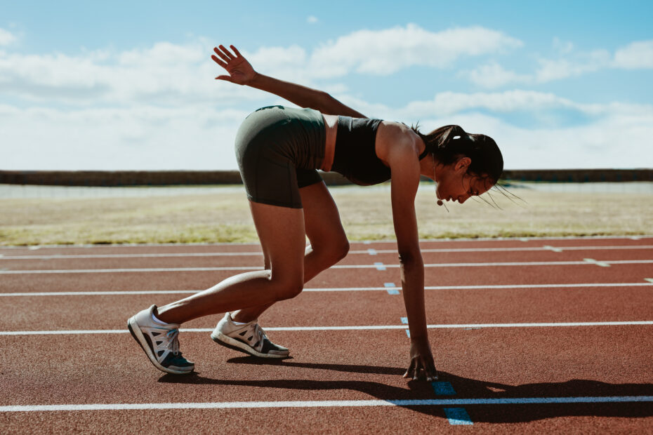 Woman runner at the start line taking position on a running trac