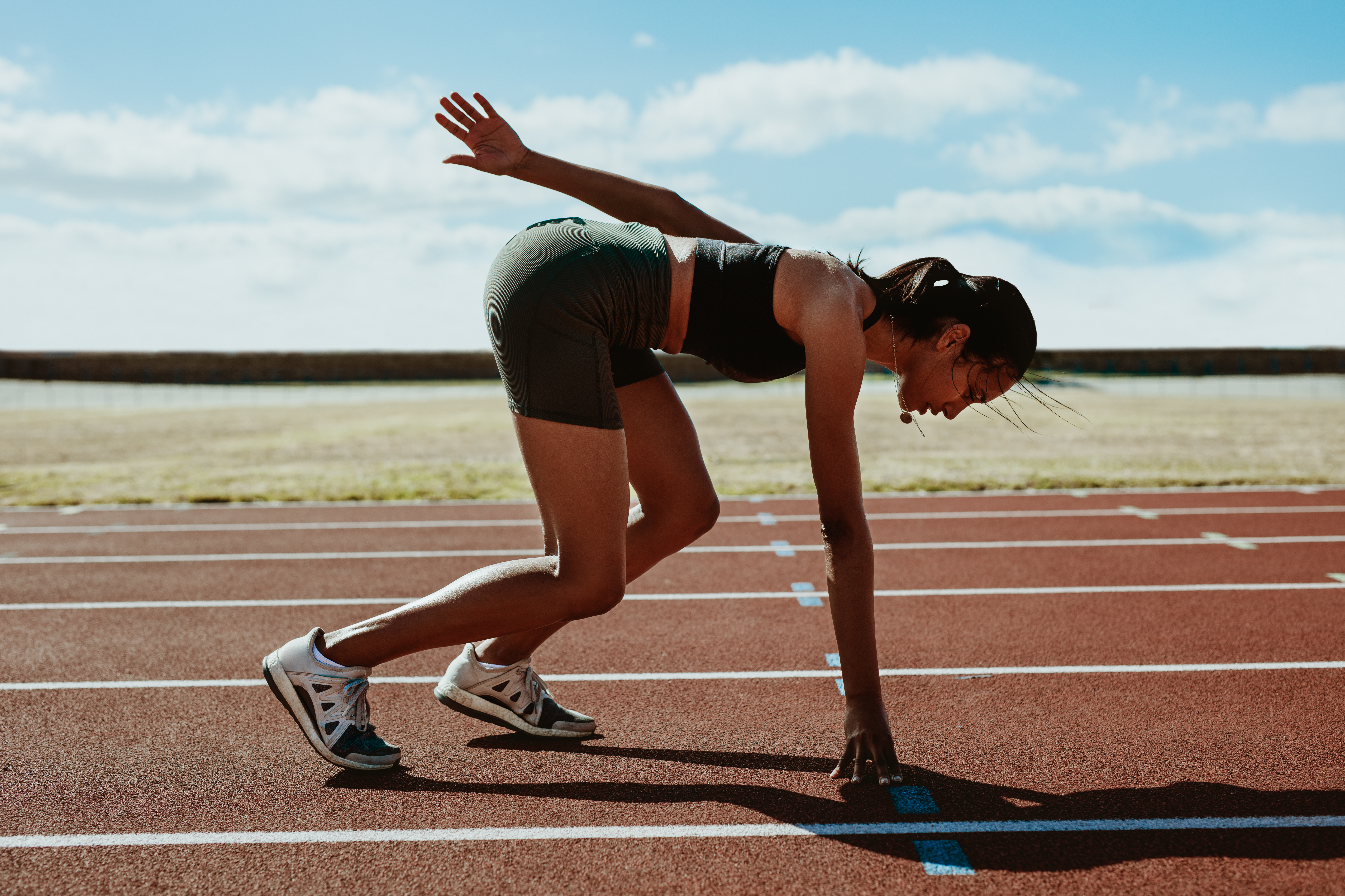 Woman runner at the start line taking position on a running trac