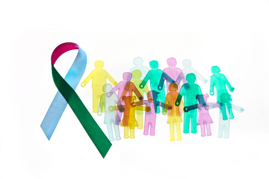 Global rare‑disease policy shifts: what are the implications for equitable access to orphan medicines? - OHE Rare Disease Day Background Colorful awareness ribbon with group of people with rare diseases