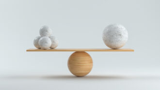 wooden scale balancing one big ball and four small ones