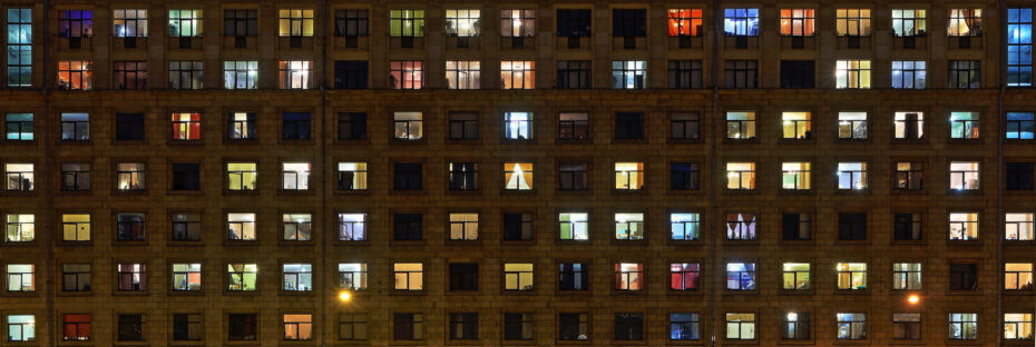 Large-format panorama of night windows of a brick, town apartment house