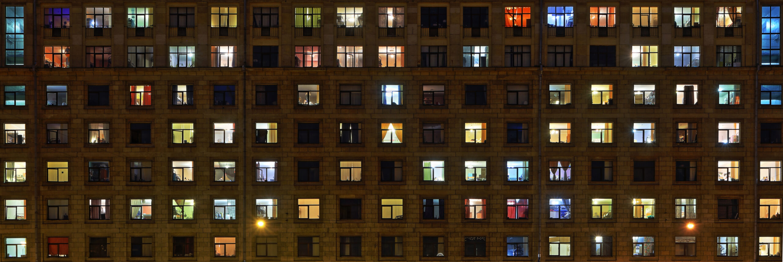 Large-format panorama of night windows of a brick, town apartment house