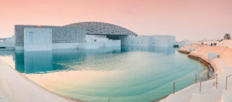 Around the world in HTAs: Abu Dhabi - Advancing HTA and value-based healthcare in the UAE - OHE Limestone and glass museum by a reflective turquoise pool at sunset with a latticed dome roof (Louvre Abu Dhabi).