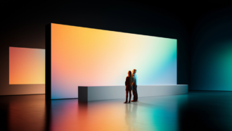 Masterclass-1 - OHE Two people stand side by side, observing a large gradient-lit display panel in a dark gallery space.