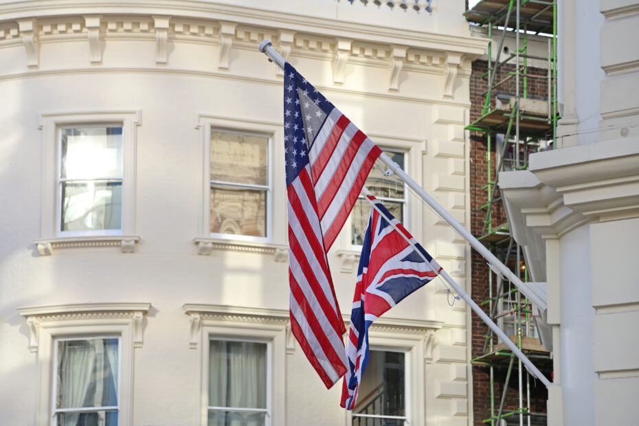 American flags on flagpoles in front of a pale, ornate building with scaffolding on the right side.