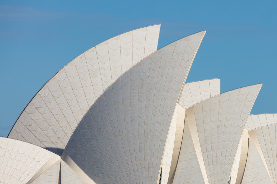 White sail-shaped roofs of the Sydney Opera House against a clear blue sky.